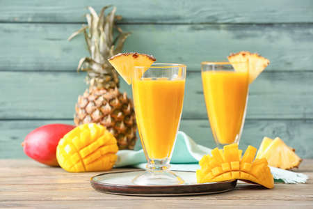 Glasses of tasty mango smoothie on color wooden backgroundの写真素材