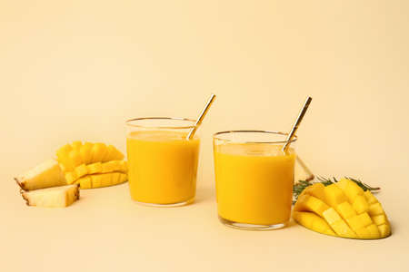 Glasses of tasty mango smoothie on color background