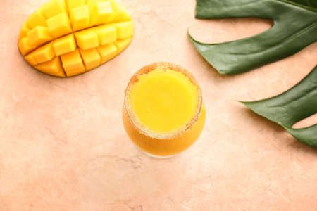 Glass of tasty mango smoothie on color backgroundの写真素材