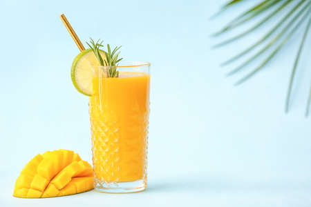 Glass of tasty mango smoothie on color backgroundの写真素材