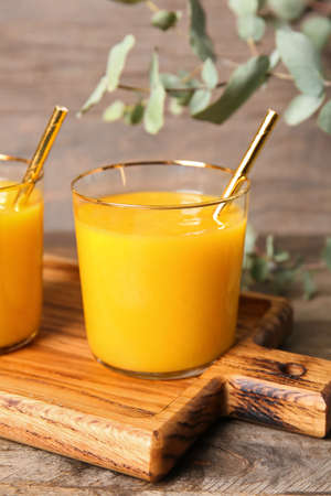 Glass of tasty mango smoothie on wooden backgroundの写真素材