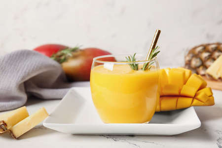 Glass of tasty mango smoothie on light backgroundの写真素材