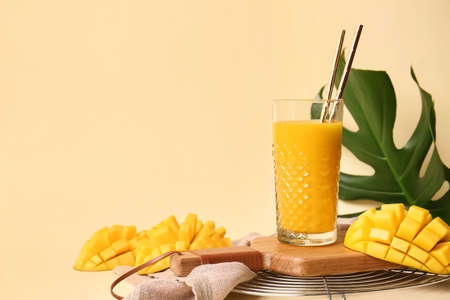 Glass of tasty mango smoothie on color backgroundの写真素材