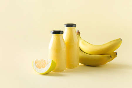 Bottles of tasty banana smoothie on color backgroundの写真素材