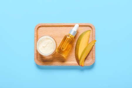 Tray with mango essential oil and cream on color backgroundの写真素材