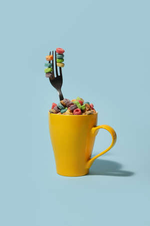 Cup with cornflakes and fork on color backgroundの写真素材