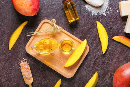 Composition with mango essential oil and bath supplies on dark backgroundの写真素材