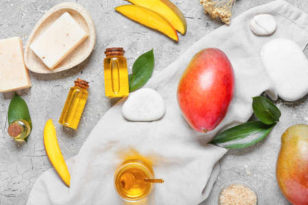 Composition with mango essential oil and bath supplies on gray backgroundの写真素材