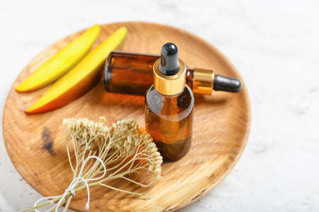 Composition with bottles of mango essential oil on light background, closeupの写真素材