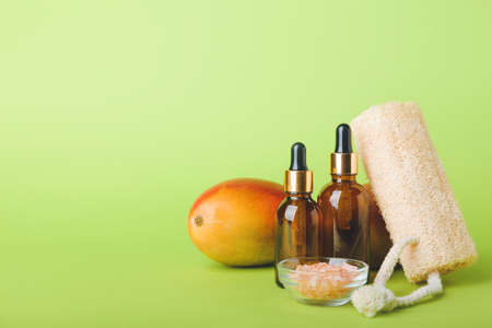 Composition with mango essential oil, sea salt and loofah on color backgroundの写真素材