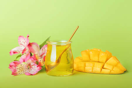 Composition with jar of mango essential oil and flowers on color backgroundの写真素材