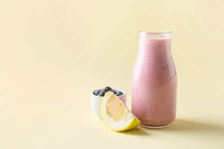 Bottle of tasty fruit smoothie on color backgroundの写真素材