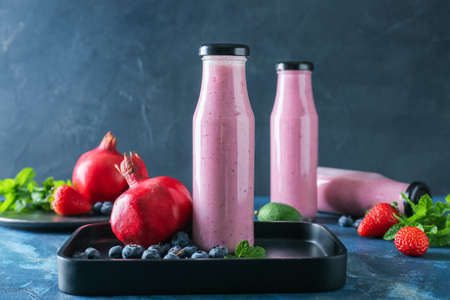 Bottles of tasty berry smoothie on color backgroundの写真素材