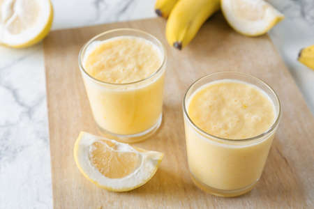 Glasses of tasty banana smoothie on light backgroundの写真素材