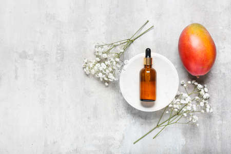 Bowl with bottle of mango essential oil on grunge backgroundの写真素材