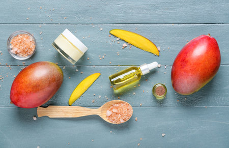 Composition with mango essential oil, sea salt and cream on color wooden backgroundの写真素材