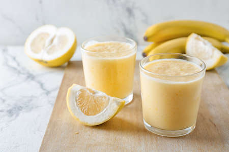 Glasses of tasty banana smoothie on light backgroundの写真素材