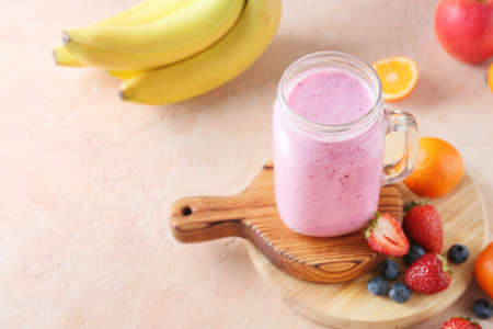Mason jar of tasty berry smoothie on color backgroundの写真素材