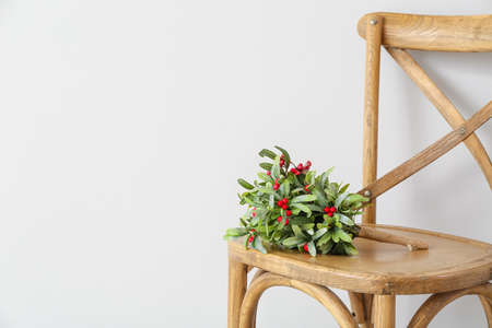 Mistletoe branch on chair against white wallの写真素材