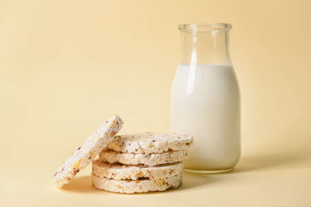 Bottle of milk and rice crackers on color backgroundの写真素材