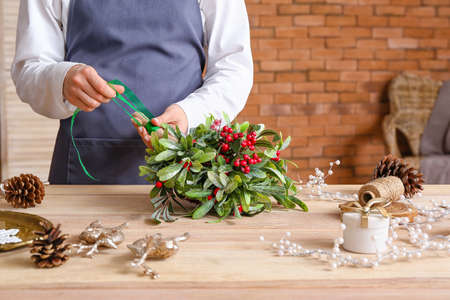 Woman making composition with mistletoe branches on tableの写真素材