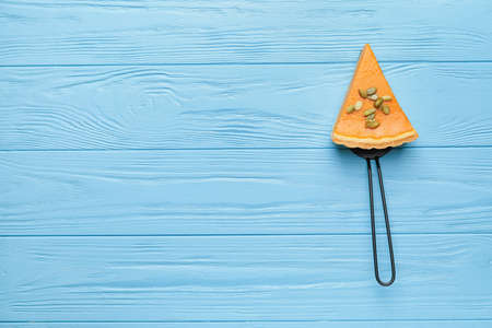 Spatula with slice of tasty pumpkin pie on color wooden backgroundの写真素材