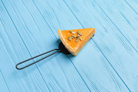 Spatula with slice of tasty pumpkin pie on color wooden backgroundの写真素材