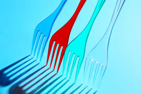 Plastic forks on color background