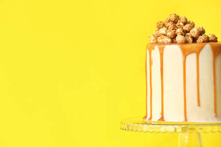 Tasty cake with popcorn and caramel on color backgroundの写真素材