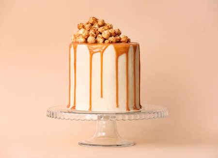 Tasty cake with popcorn and caramel on color backgroundの写真素材