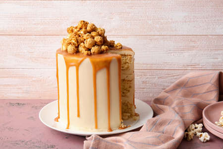 Tasty cake with popcorn and caramel on color wooden backgroundの写真素材
