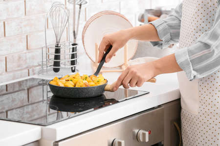Woman cooking potato with garlic in kitchenの写真素材