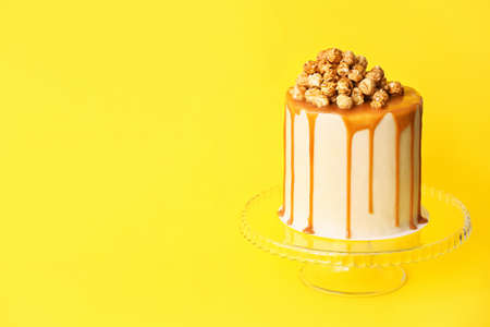 Tasty cake with popcorn and caramel on color backgroundの写真素材