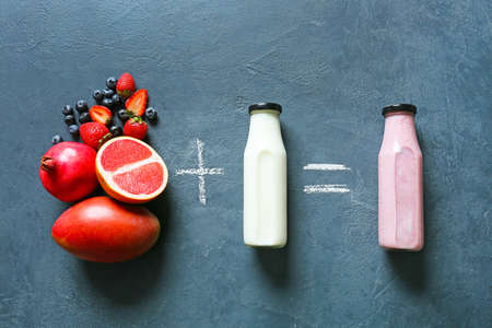 Composition with bottles of tasty smoothie, milk and fruits on dark backgroundの写真素材