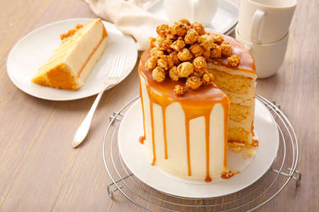 Tasty cake with popcorn and caramel on light wooden backgroundの写真素材