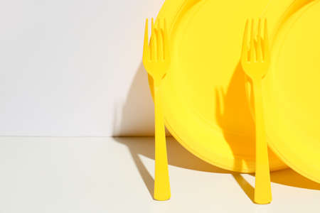 Plastic forks and plates on color backgroundの写真素材
