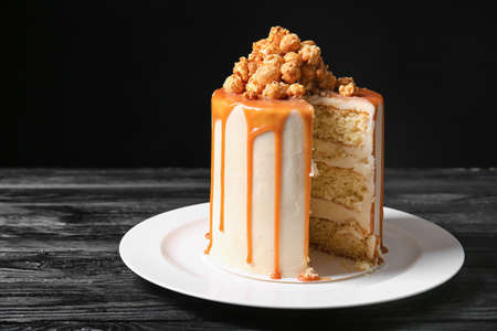 Tasty cake with popcorn and caramel on dark wooden backgroundの写真素材