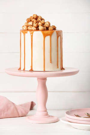 Tasty cake with popcorn and caramel on light wooden backgroundの写真素材