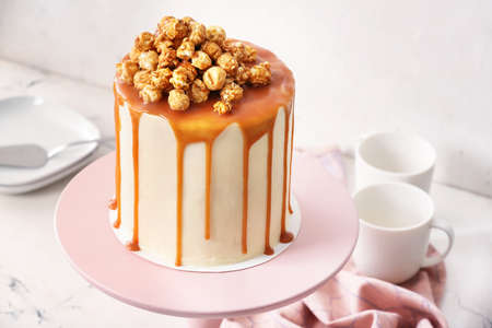 Tasty cake with popcorn and caramel on light backgroundの写真素材