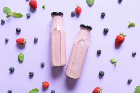 Bottles of tasty smoothie with berries on color backgroundの写真素材