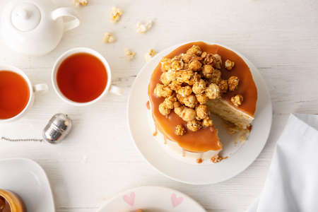 Tasty cake with popcorn and caramel on light wooden backgroundの写真素材