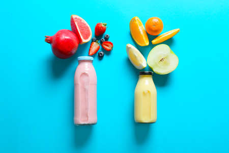 Bottles of tasty smoothie with fruits on color backgroundの写真素材