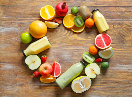 Frame made of bottles with tasty smoothie and fruits on wooden backgroundの写真素材