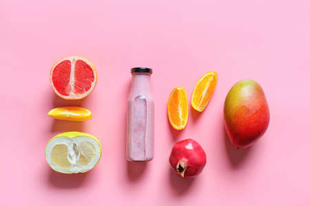 Bottle of tasty smoothie with fruits on color backgroundの写真素材