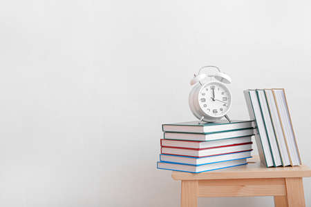 Shelf unit with books and alarm clock against light wall in roomの写真素材