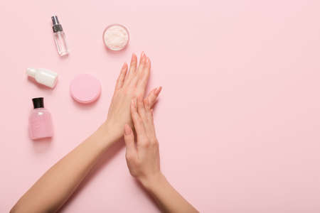 Female hands with cosmetic products on color backgroundの写真素材
