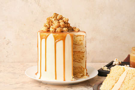 Tasty cake with popcorn and caramel on grunge background