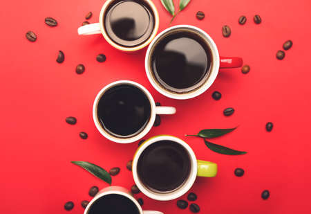 Cups of tasty coffee and beans on color background