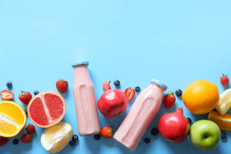 Bottles of tasty smoothie with fruits on color background