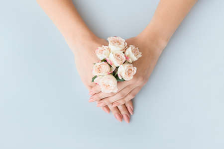 Female hands with beautiful flowers on color background